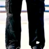 Black cargo pants with multiple side pockets, relaxed fit, and sneakers, shown from the back in an outdoor setting.