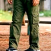 Olive green cargo pants with multiple flap pockets, relaxed fit, and black sneakers, worn outdoors on a natural ground setting.