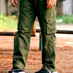 Olive green cargo pants with multiple flap pockets, relaxed fit, and black sneakers, worn outdoors on a natural ground setting.