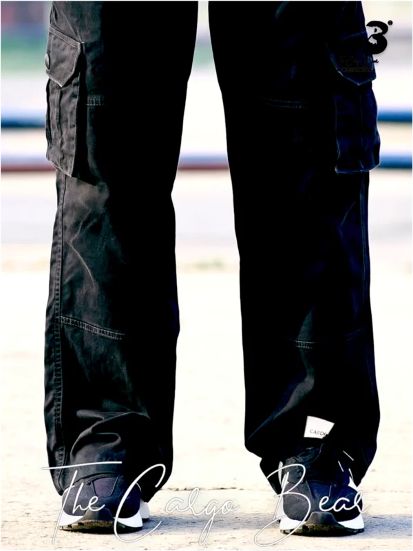 Black cargo pants with multiple side pockets, relaxed fit, and sneakers, shown from the back in an outdoor setting.